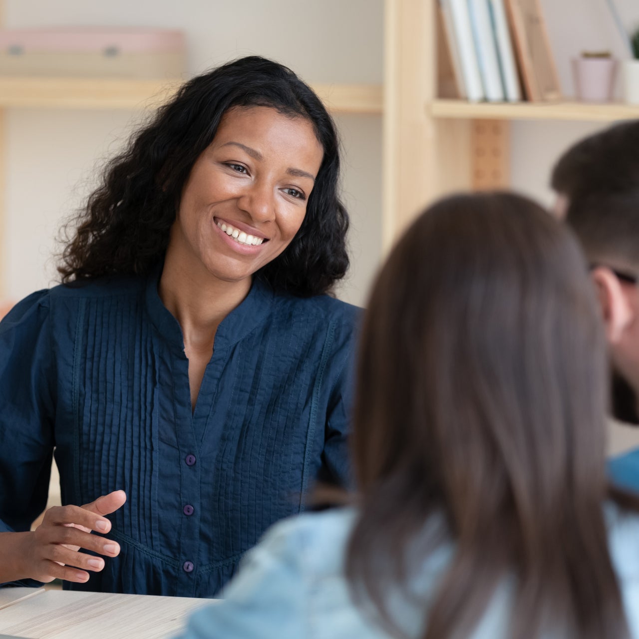 Three people are sitting on a desk and having a discussion.