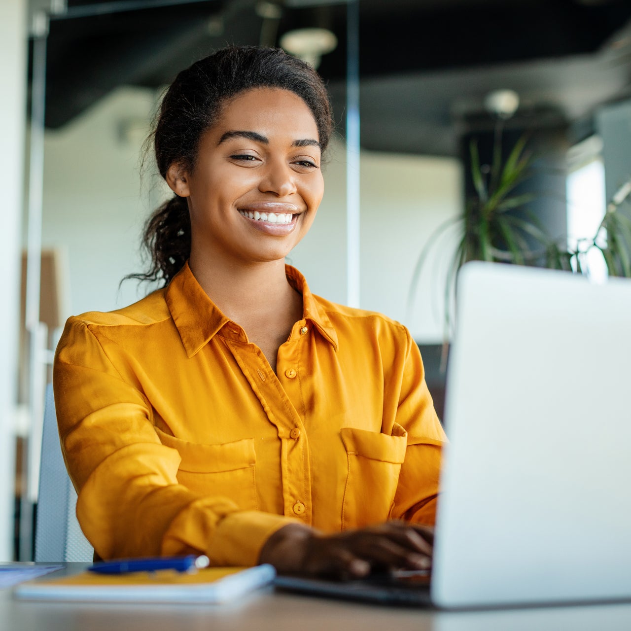 A cheerful young professional woman working on laptop.