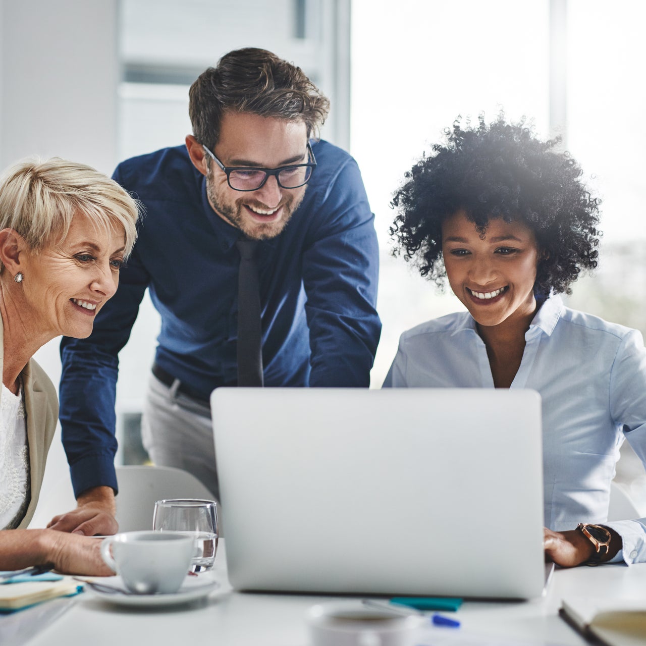 A modern office with workers collaborating at a laptop