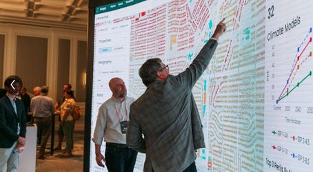 CotalityConnect visitor pointing at a large screen showing property data visualization