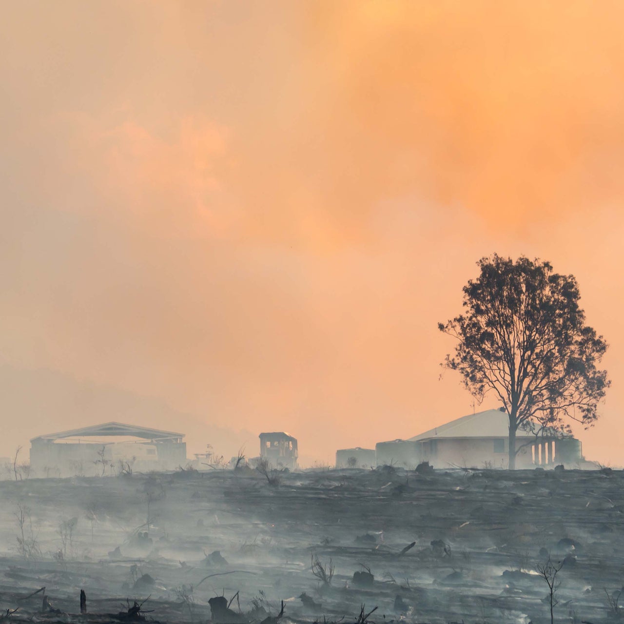 Three people stand outside a modern house, with one person holding a tablet and gesturing, discussing property details.