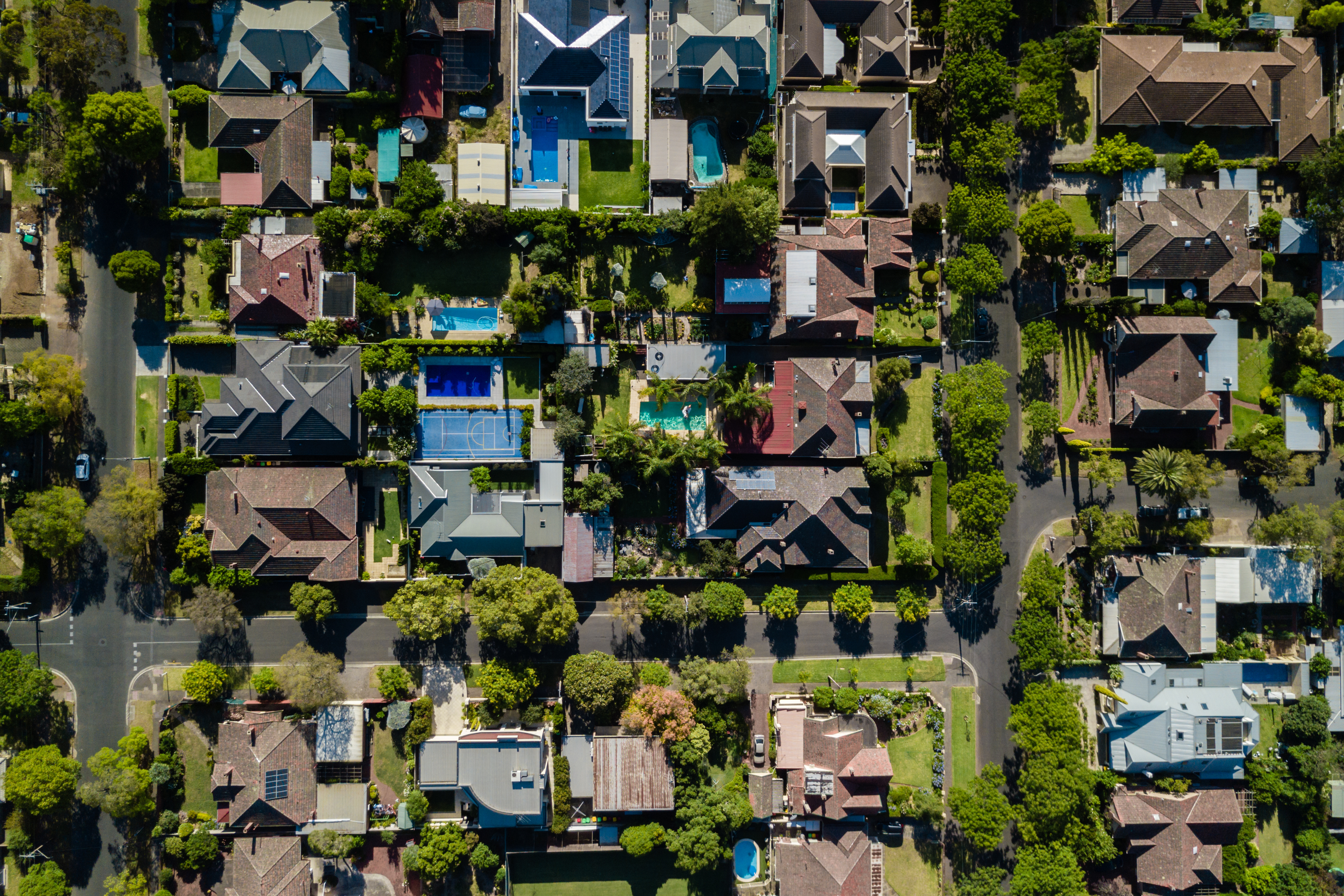 Aerial view of a suburban neighborhood with houses, backyards and pools.