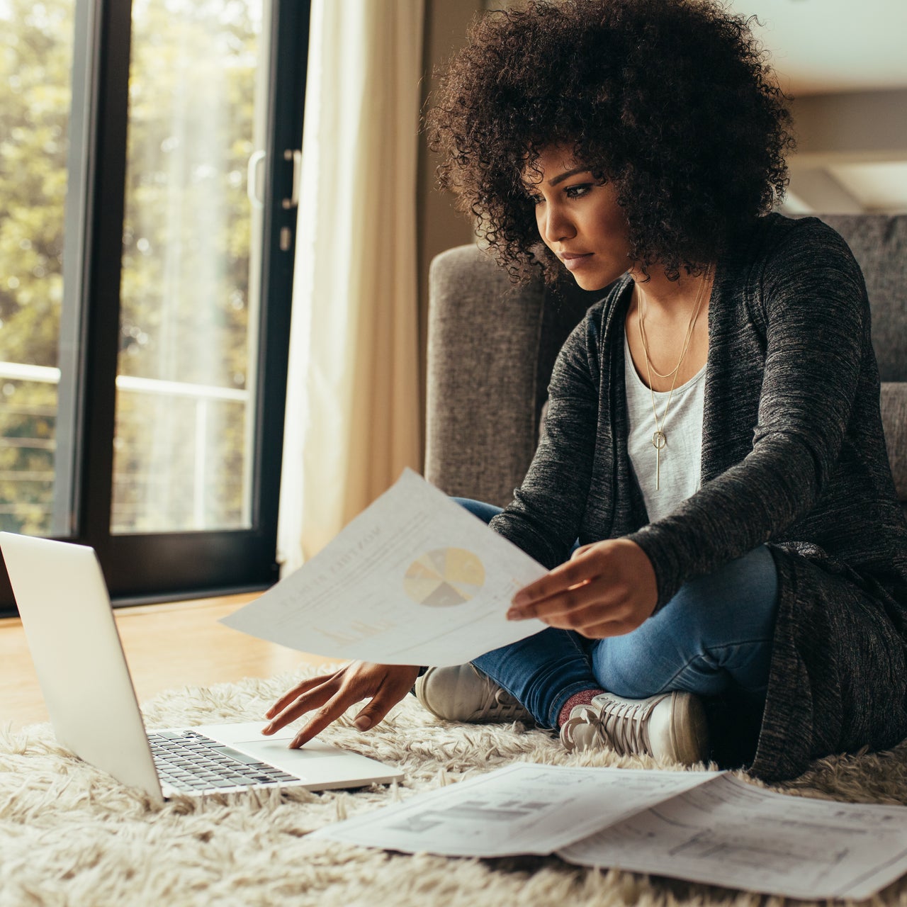 A woman working on a tablet and with sone papers in hand.