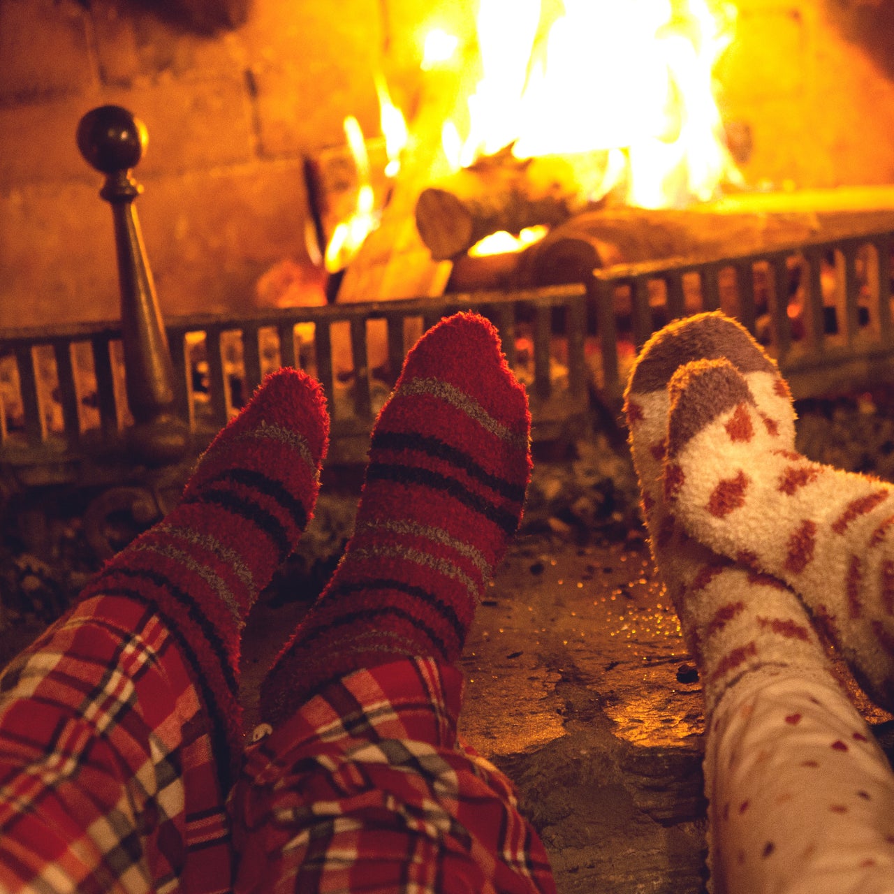 A mother helping her toddler put a bandage in one of his toes. The toddler is in a sitting position while the mother is standing.
