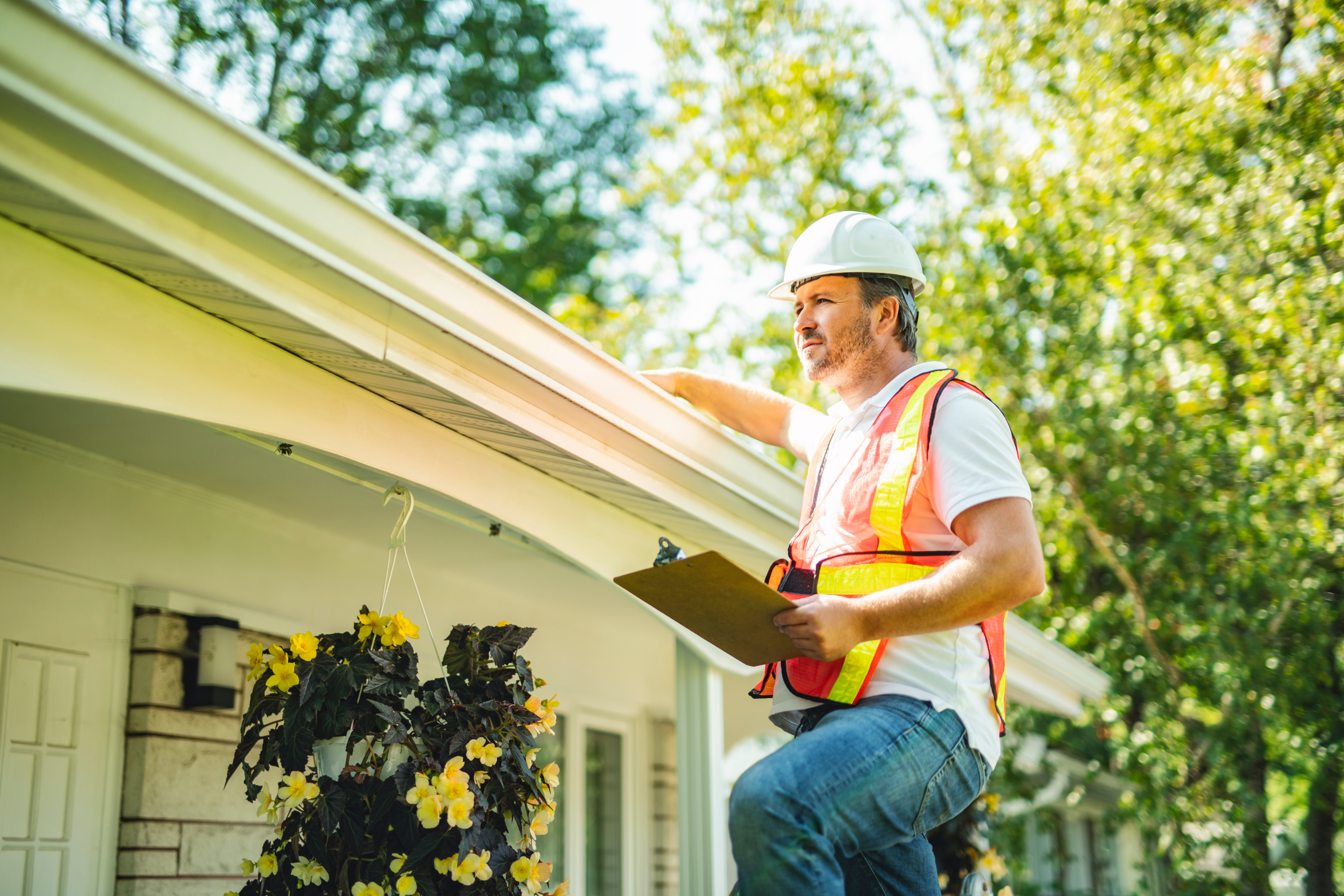 A construction worker inspecting the roof of a house.