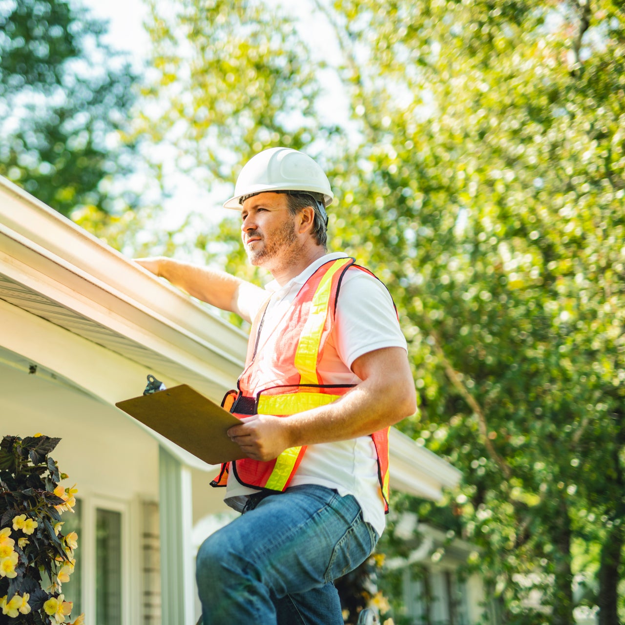 A construction worker inspecting the roof of a house.