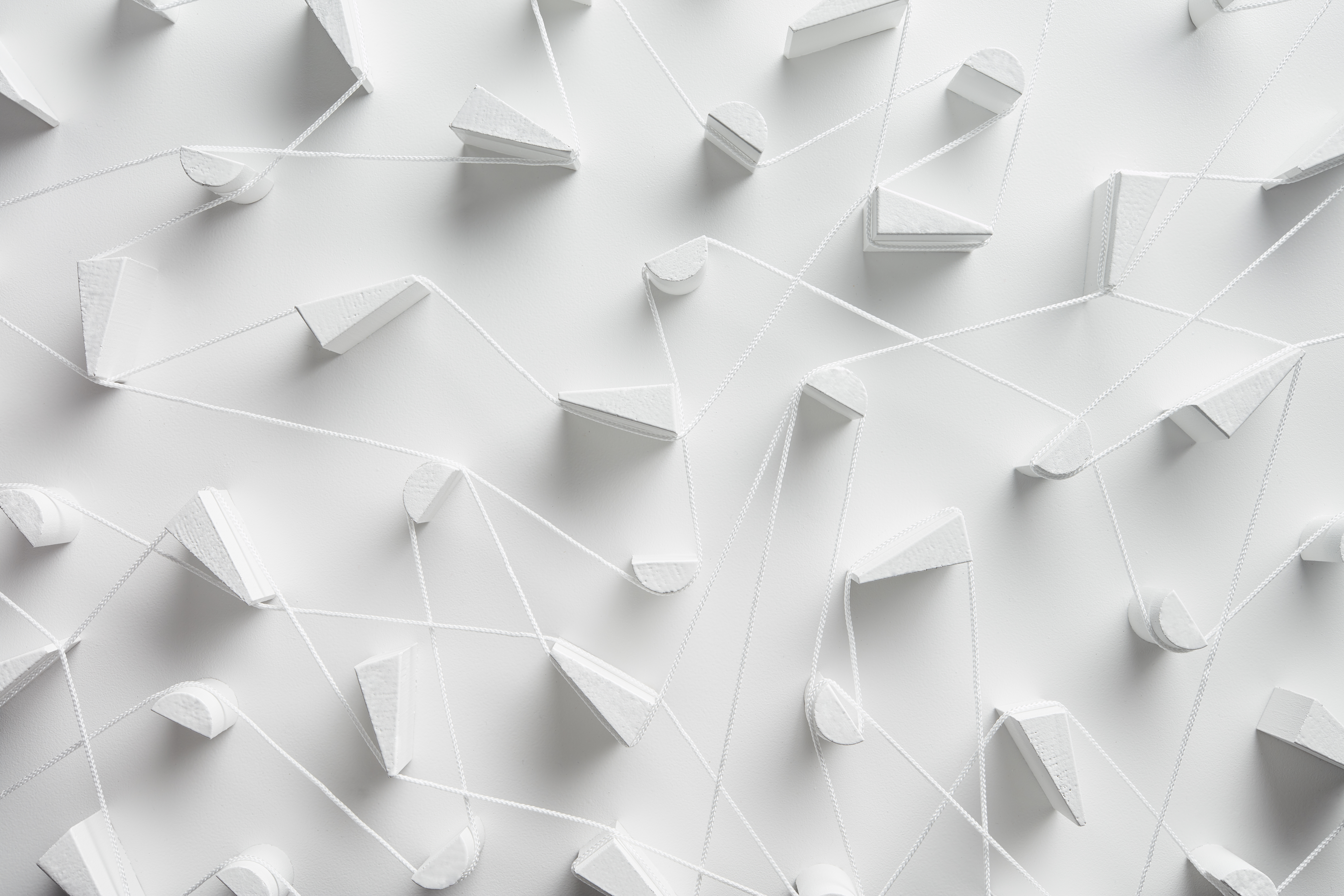 A close-up, high-angle view of a white 3D art installation featuring various geometric shapes.