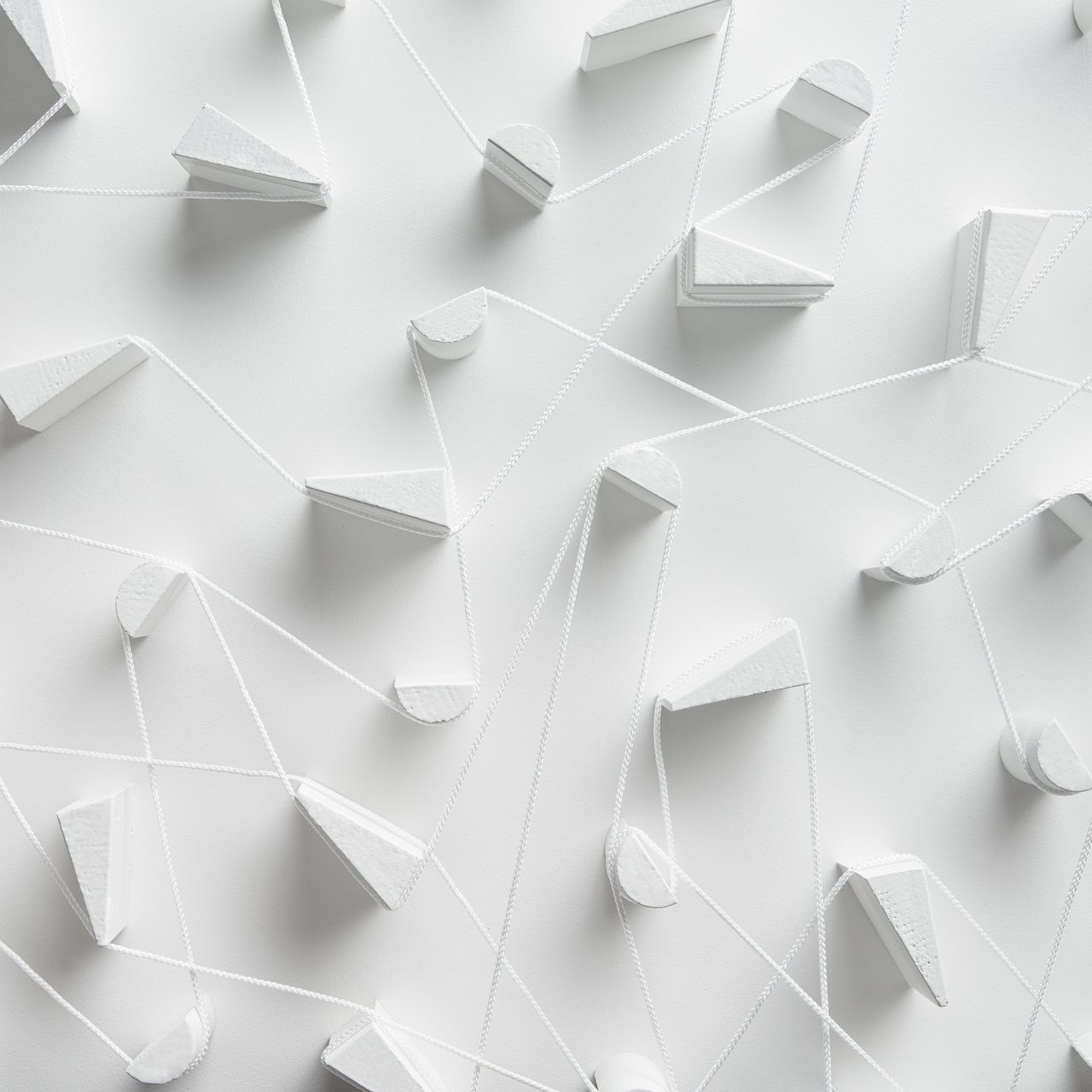 A close-up, high-angle view of a white 3D art installation featuring various geometric shapes.