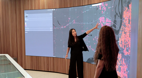 two presenter in front of a large screen showing property data visualization on a map at the Cotality Discovery Center