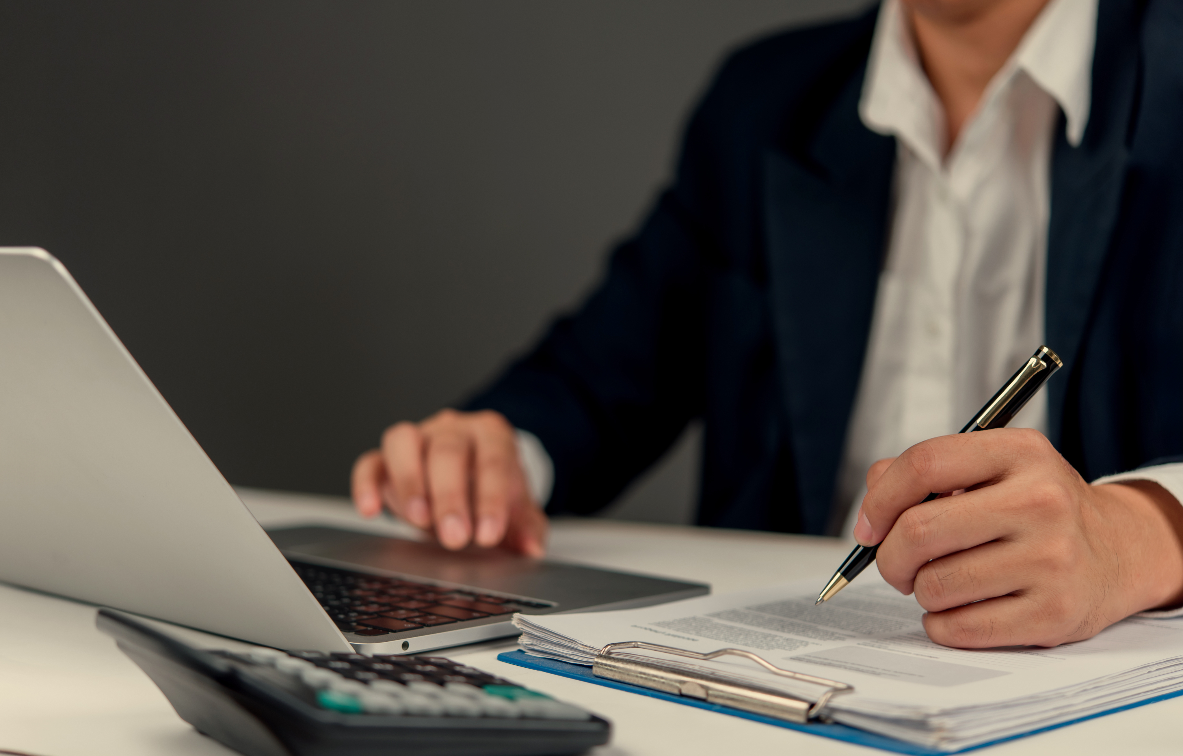 A hand is visible working on a laptop kept on a desk.