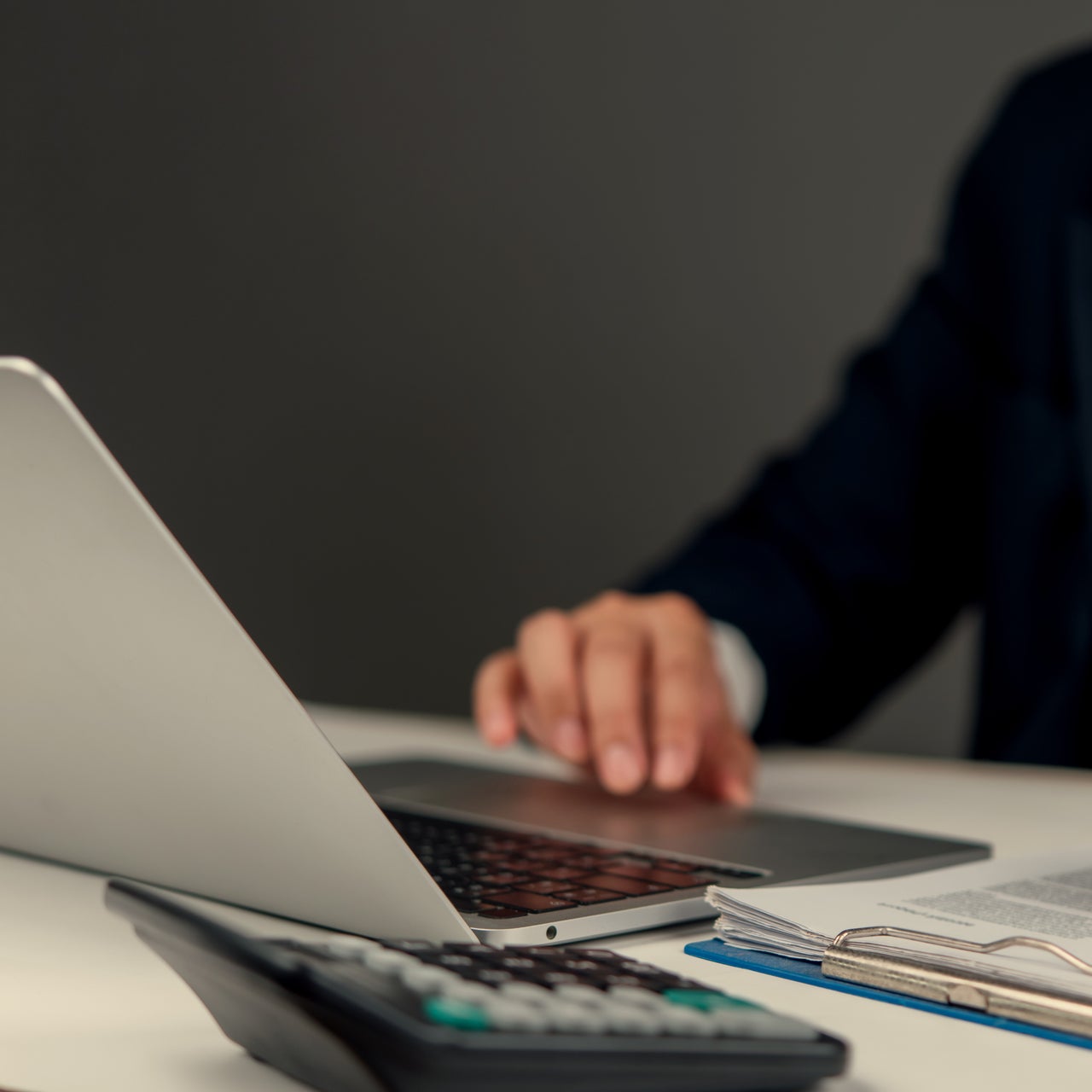 A hand is visible working on a laptop kept on a desk.