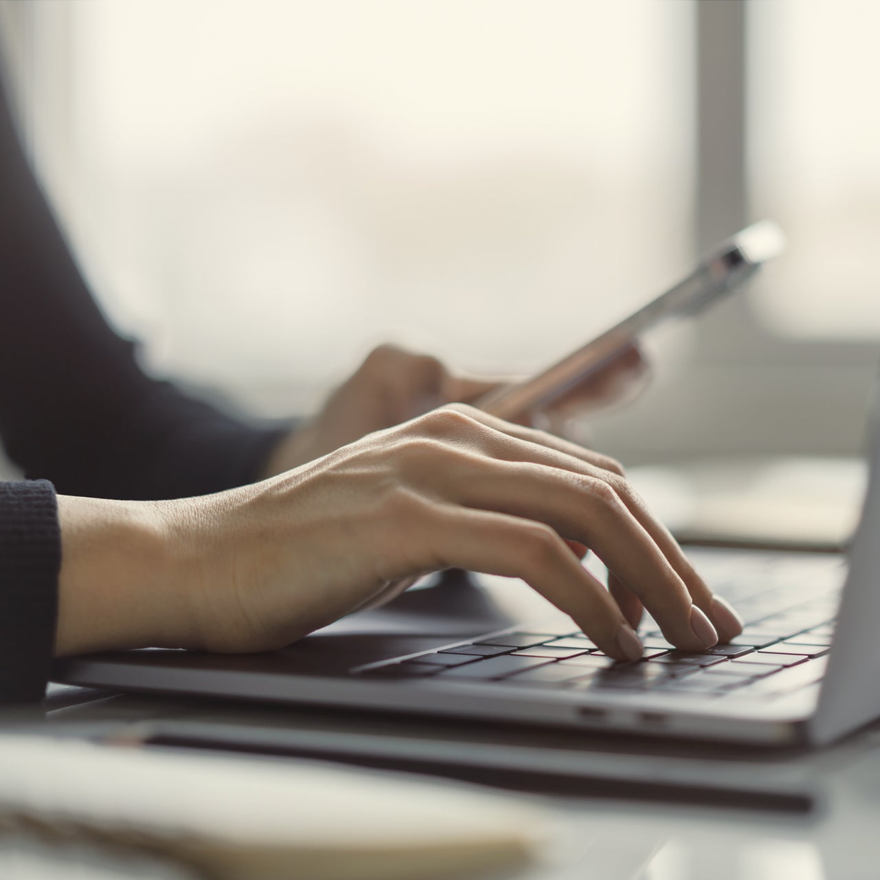 Someone' hand is shown working on a laptop.