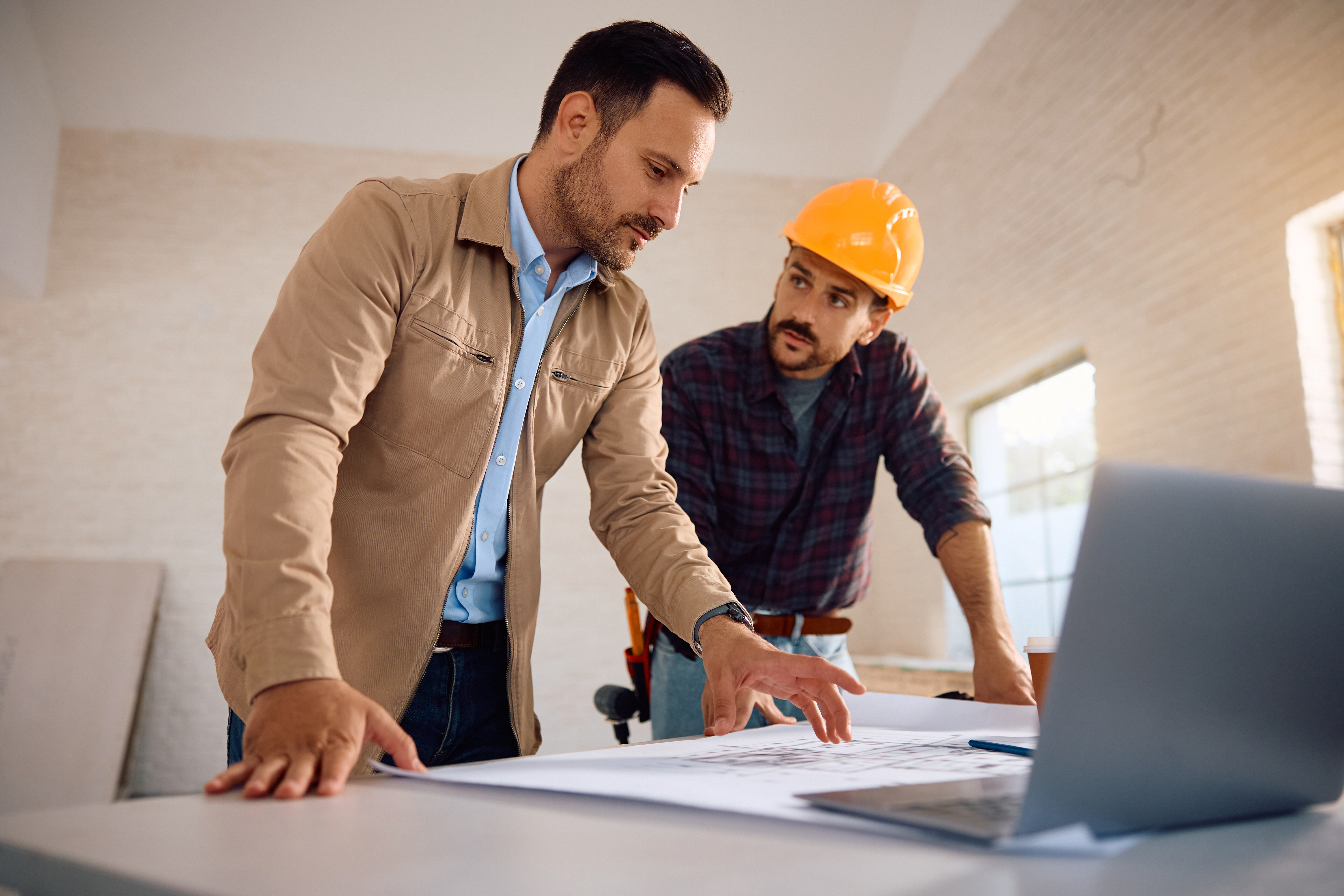 A local assessor and a contractor reviewing site blueprints to verify property specs and ensure fair valuations.