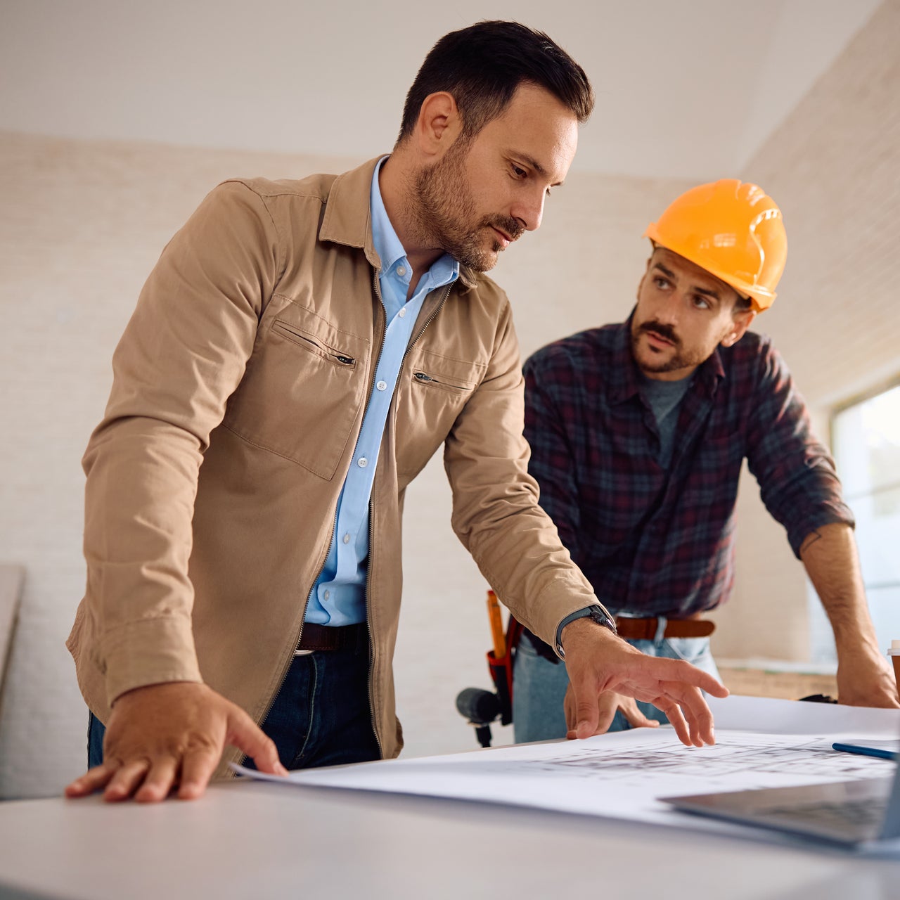 A local assessor and a contractor reviewing site blueprints to verify property specs and ensure fair valuations.