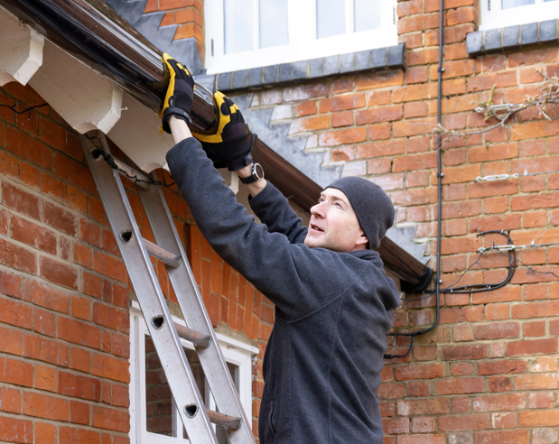 A man is seen up on a ladder, fixing something.