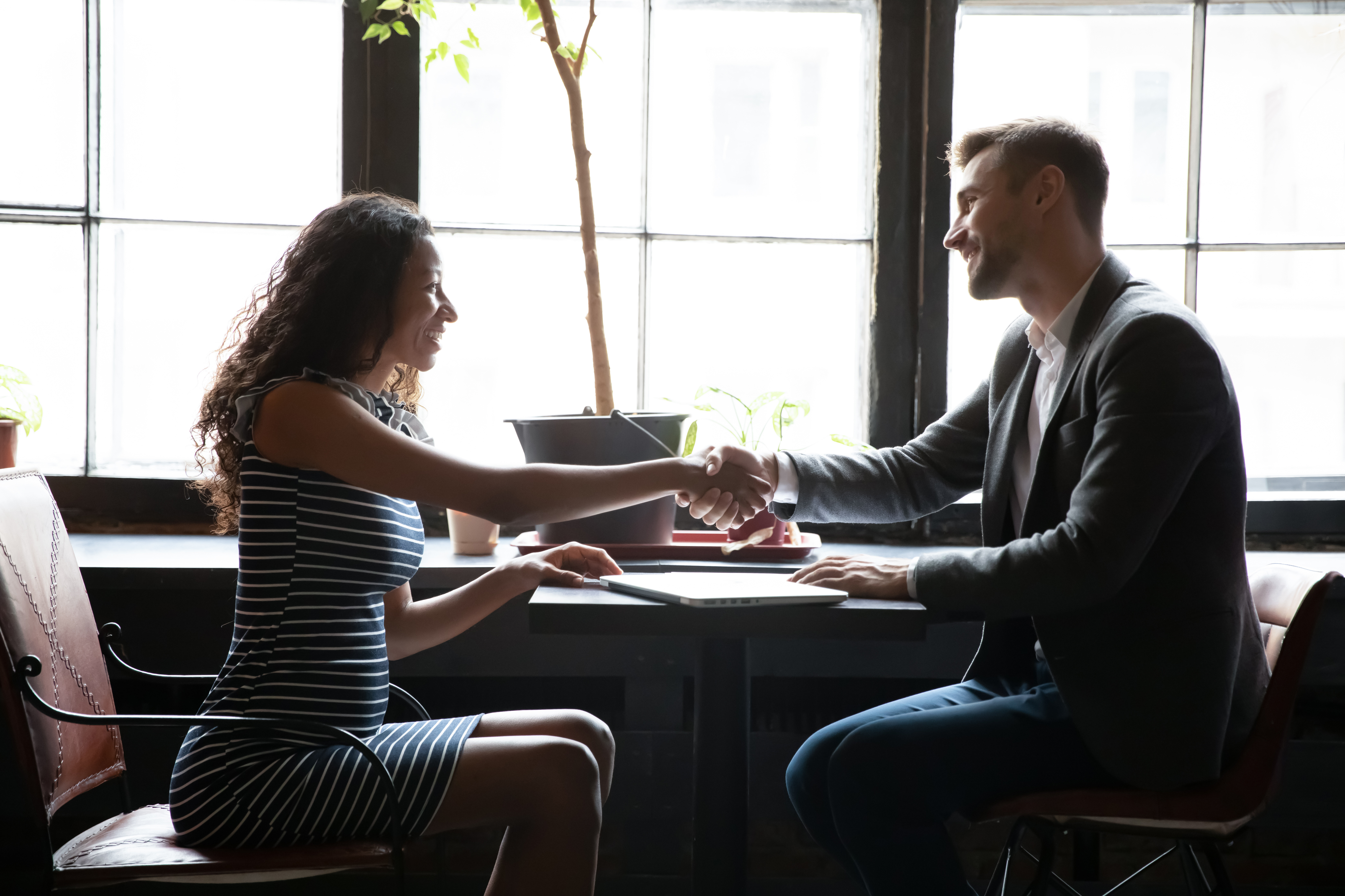 A man and woman shaking hands in a business setting.