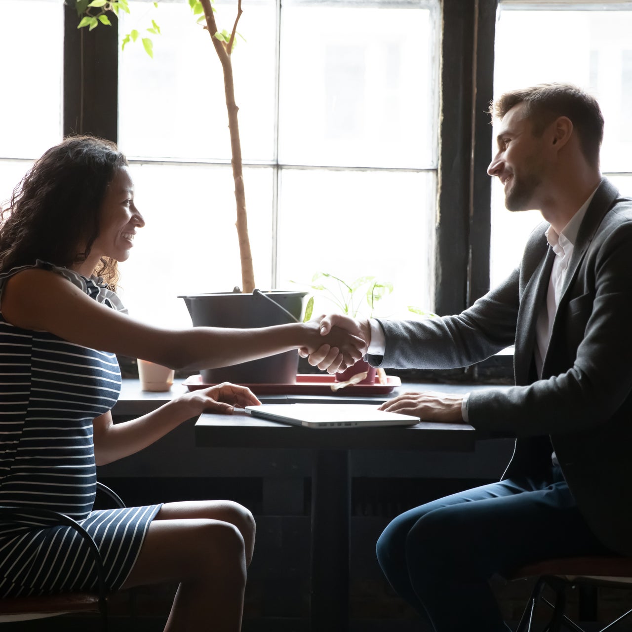A man and woman shaking hands in a business setting.