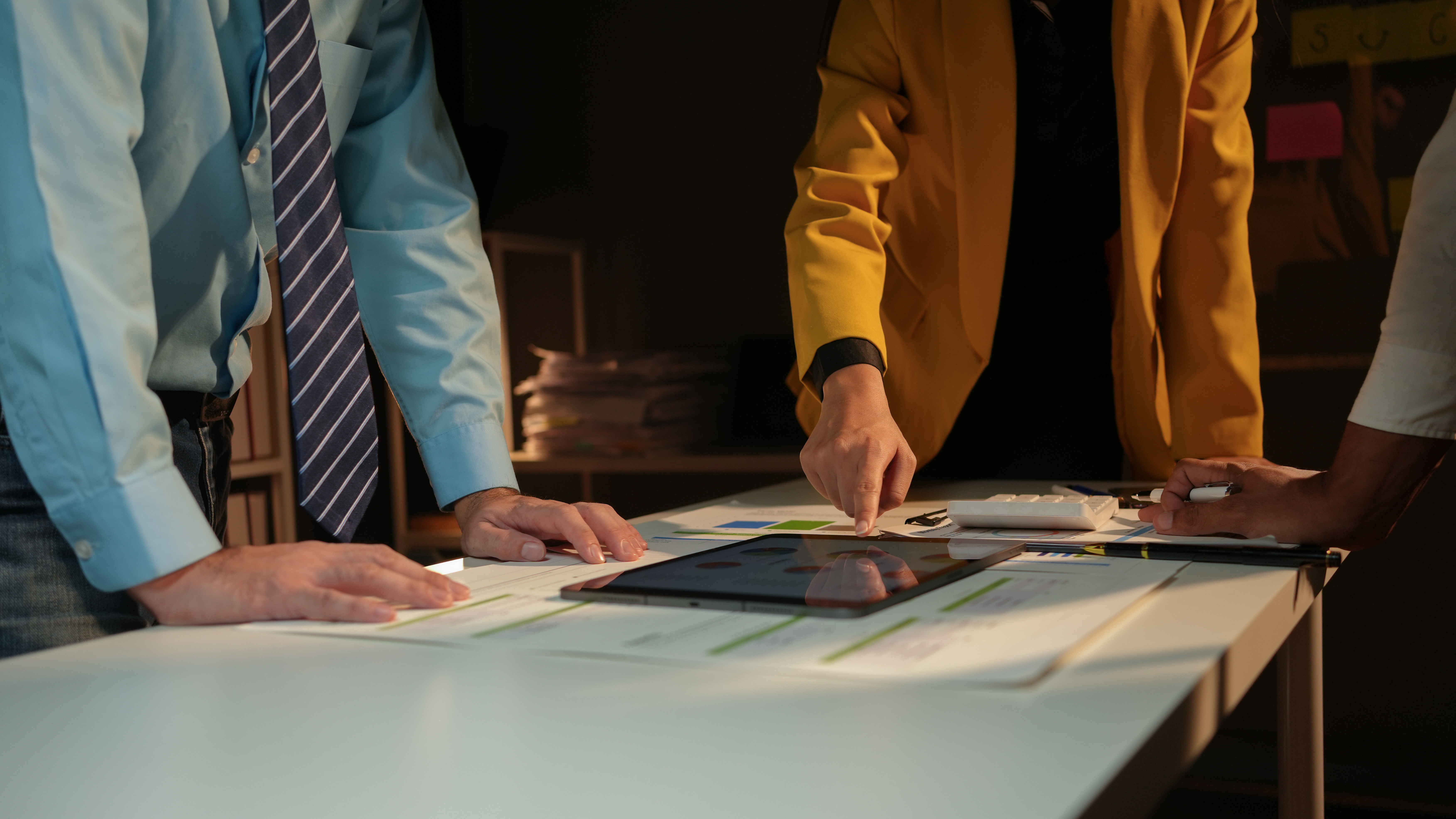 Team of business professionals are working late in the office, illuminated by a warm light, as they collaborate on a project.