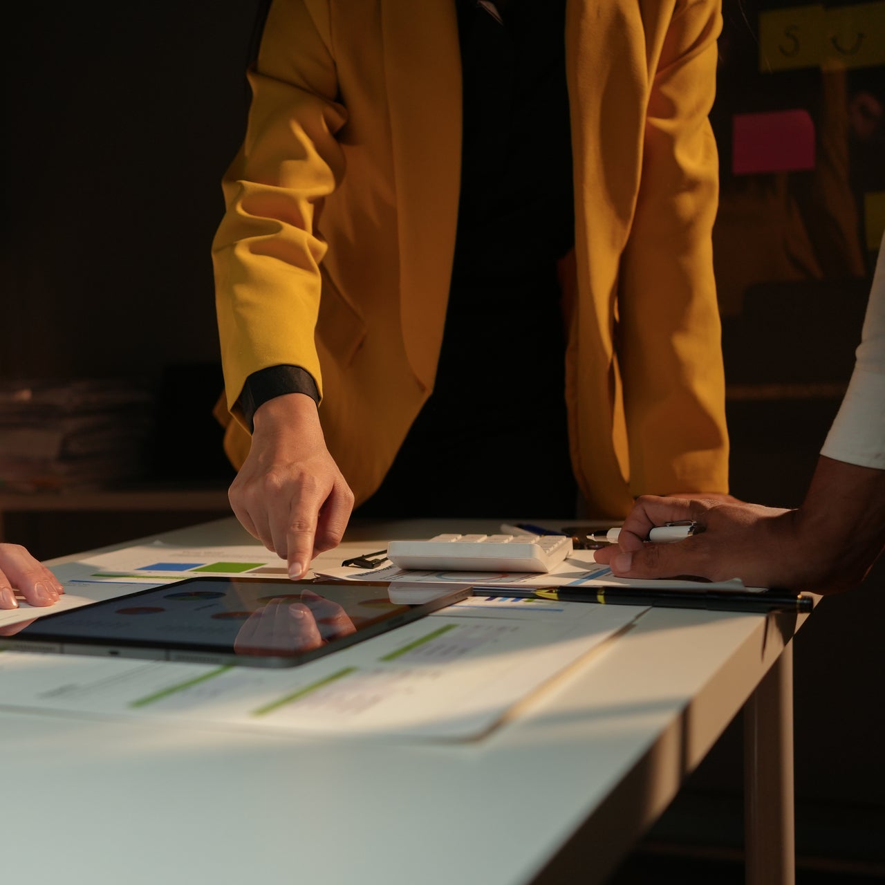 Team of business professionals are working late in the office, illuminated by a warm light, as they collaborate on a project.