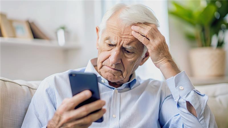 A senior citizen looking at their mobile device with a puzzled expression