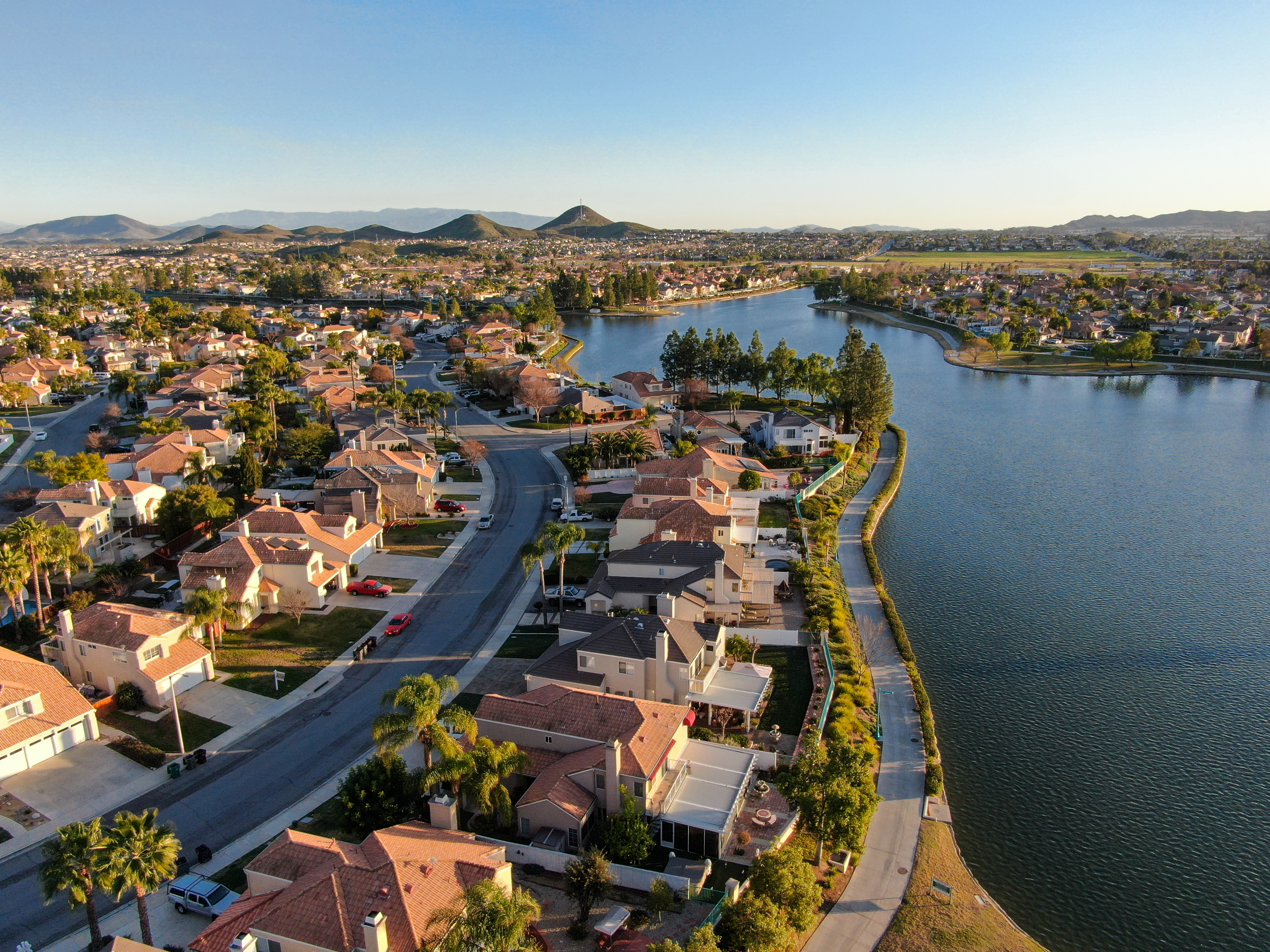An aerial view of a suburban neighborhood with a lake in the background.