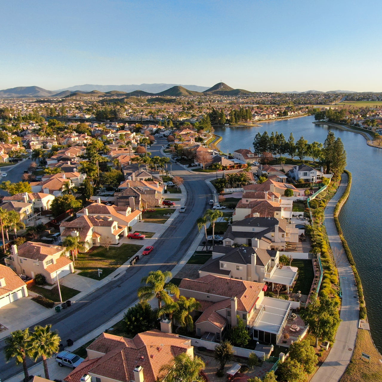 An aerial view of a suburban neighborhood with a lake in the background.
