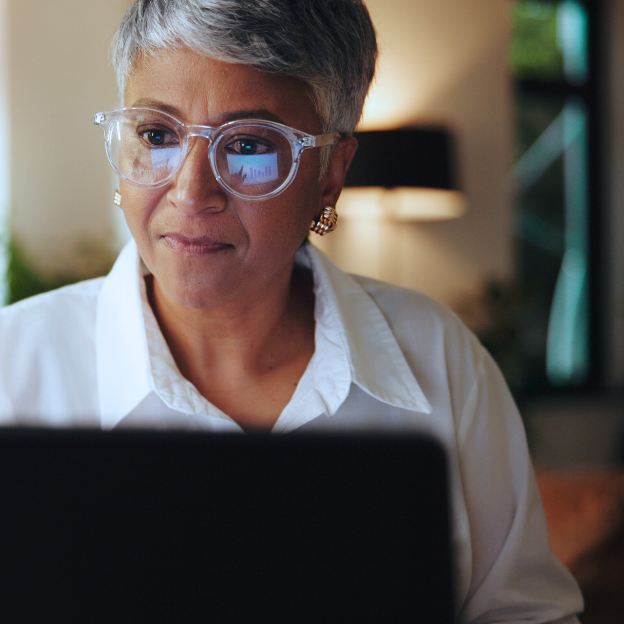 A woman in glasses using a secure state government website on her computer to access public services.