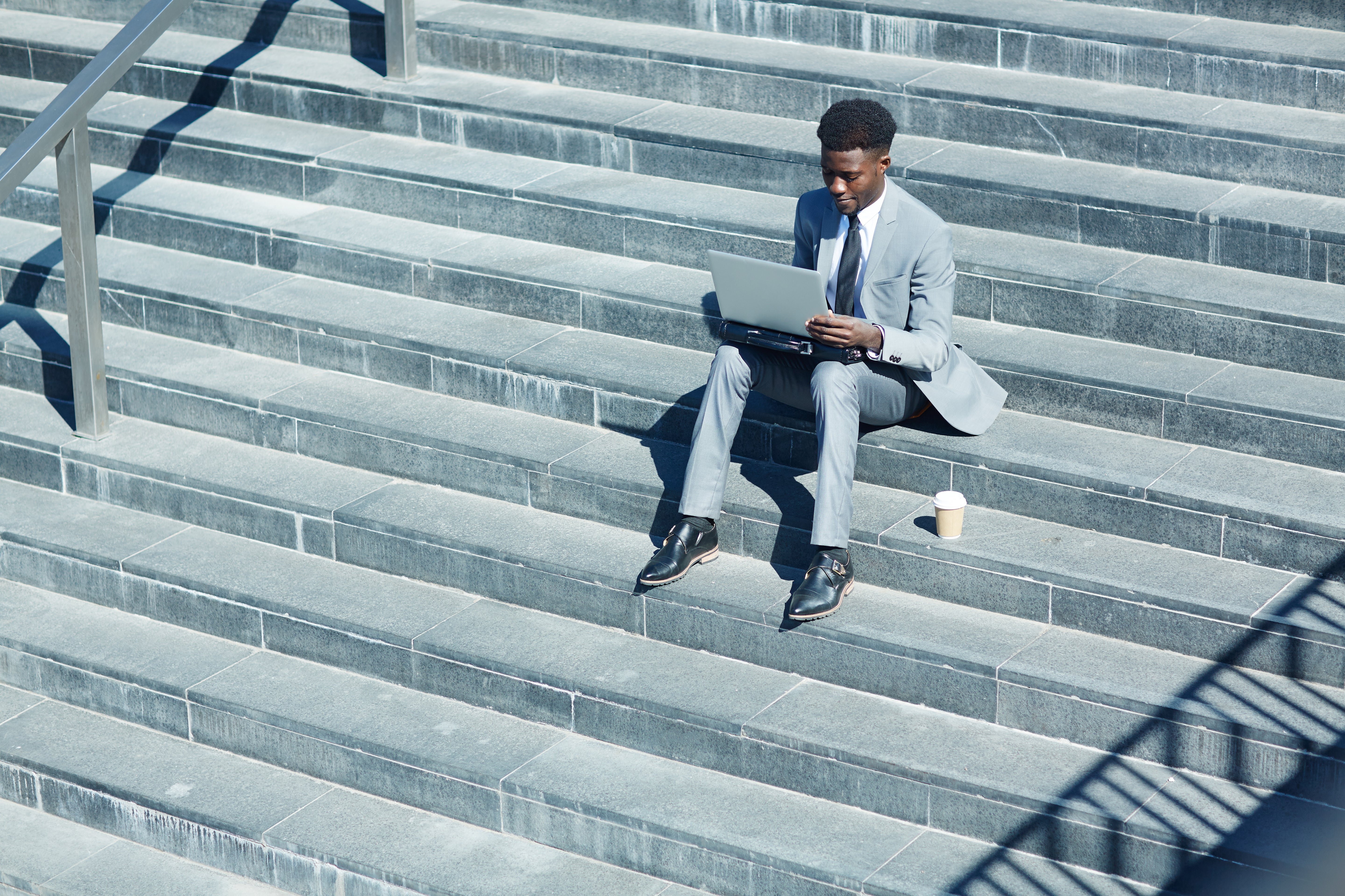 business man sitting on steps with laptop