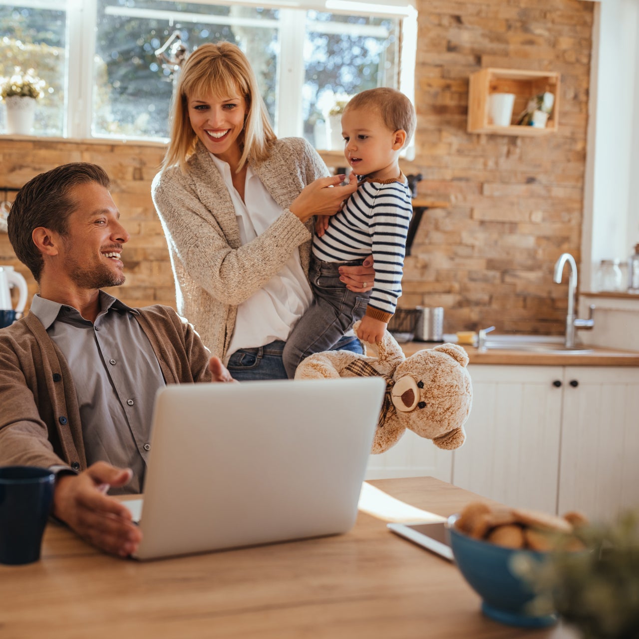 A family of three, a couple and a child looking into the laptop screen and smiling.