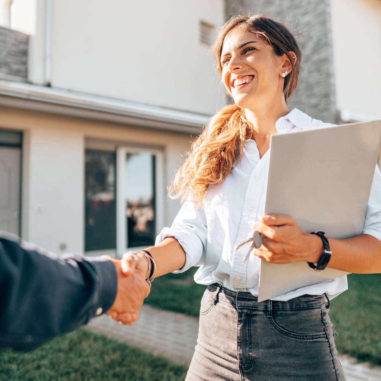 A real estate agent is seen handing over house keys to a client after a successful property sale.