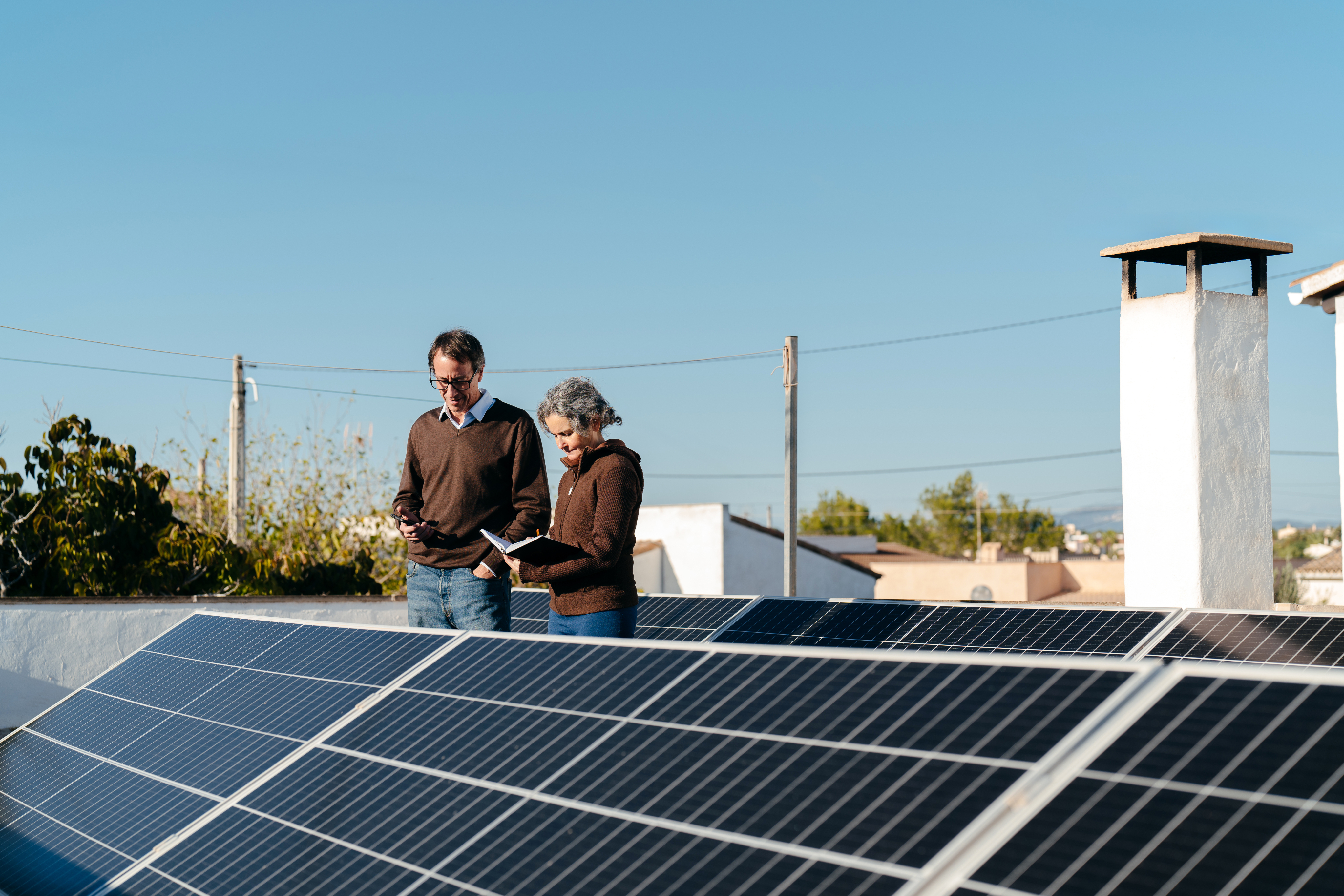 A man and a woman reading a document in front of solar panels.