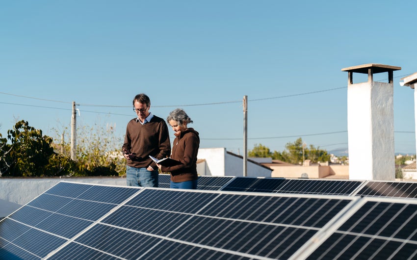 A man and a woman reading a document in front of solar panels.