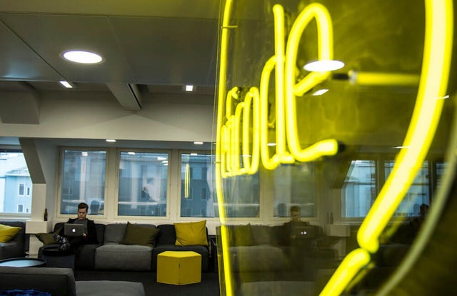 A person reading on a laptop at the eficode office with a large neon eficode logo