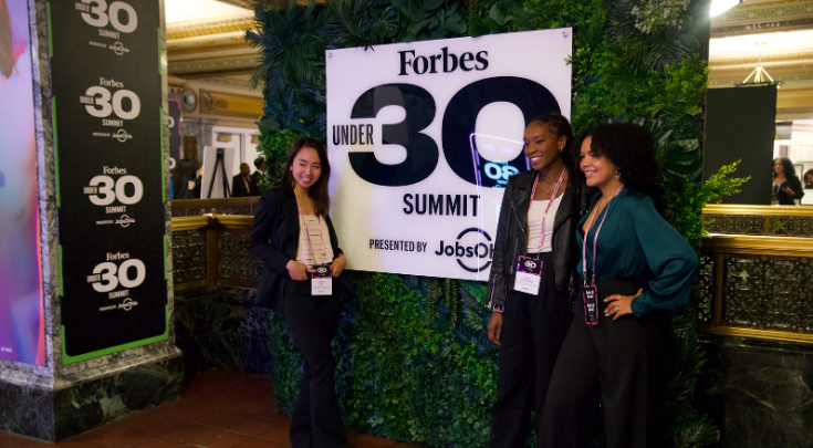 Attendees pose with the Forbes Under 30 Summit sign