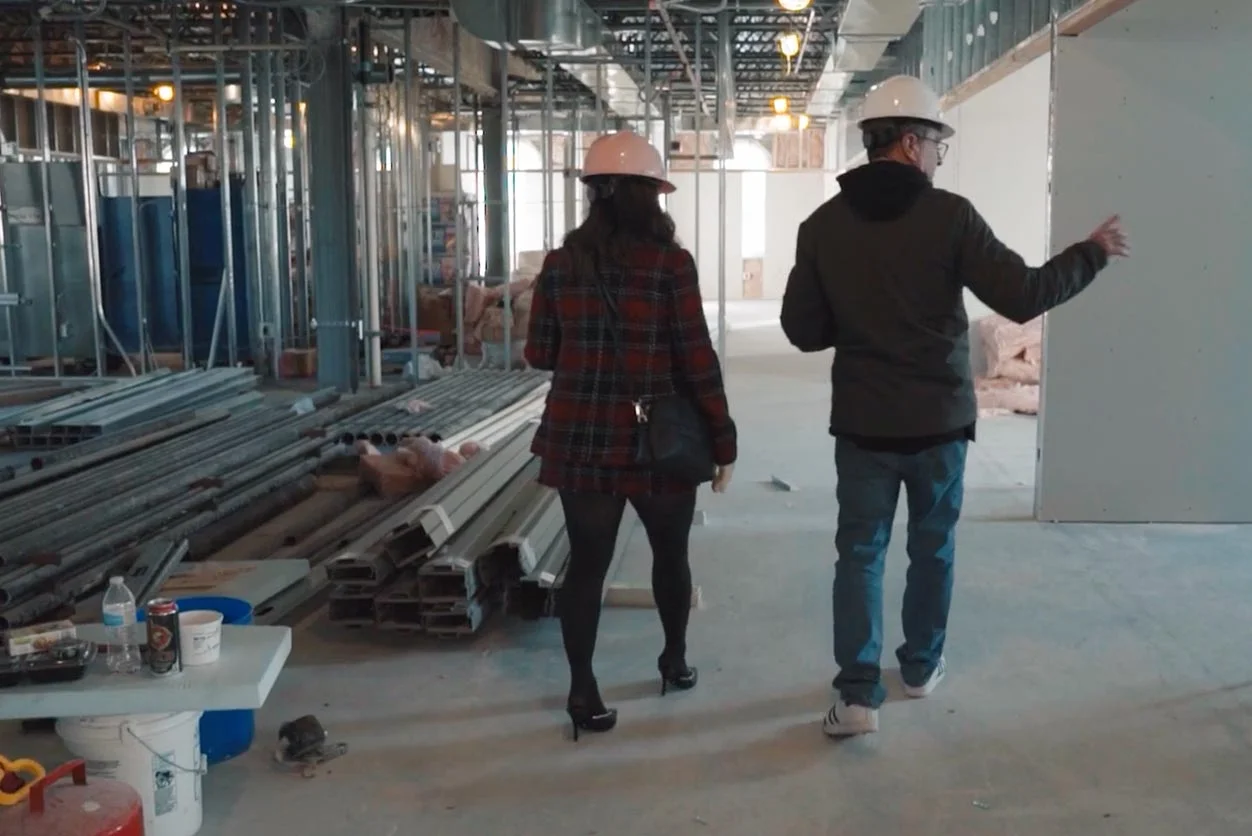2 people in hard hats walking in construction