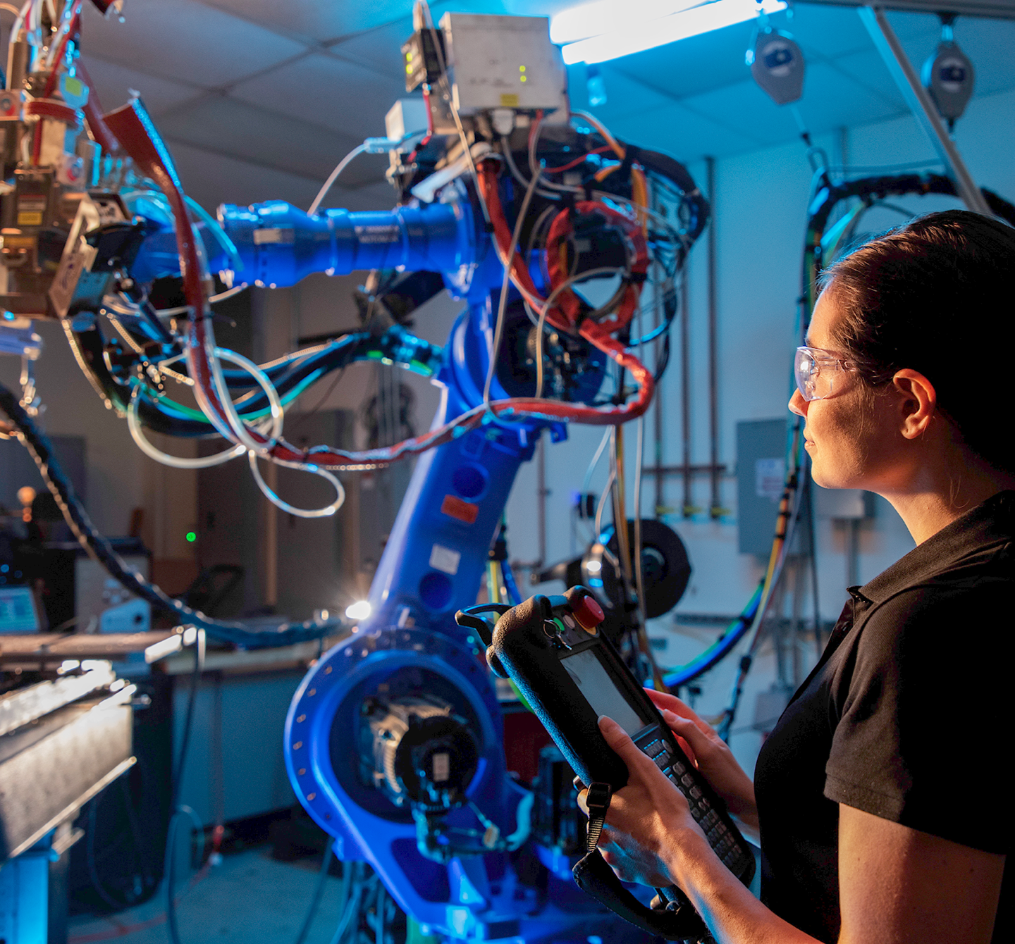 A woman in safety glasses working on a machine