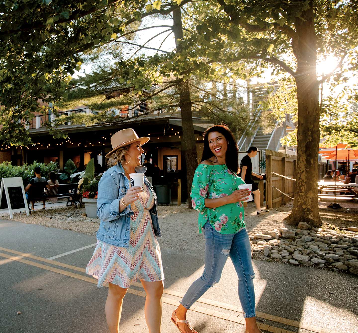 Two women walking down an urban street with drinks