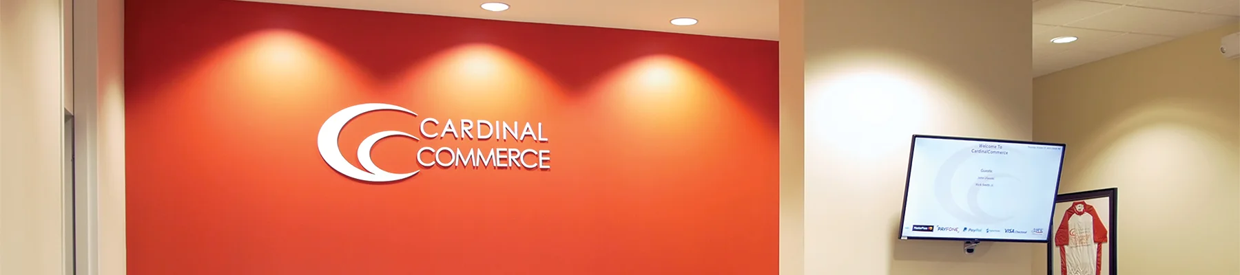 Cardinal Commerce logo on an orange wall with lights