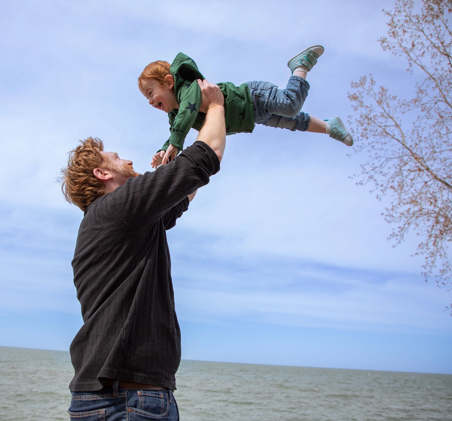 A man playing outside by the lake with a child