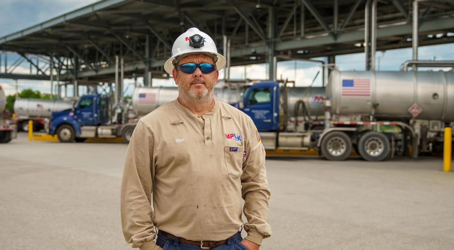 A man in a construction hat with gas trucks in the background
