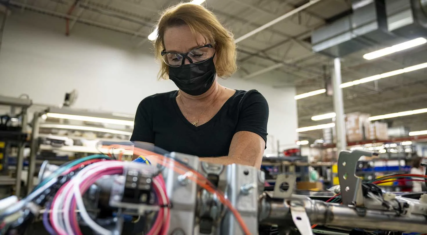 A woman in a factory wearing a mask