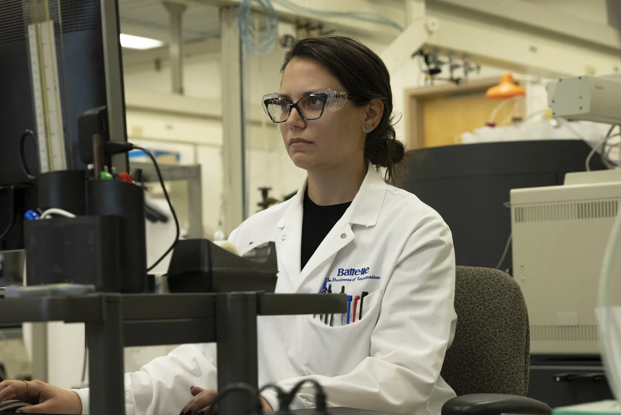 A woman working in a lab with a Battelle lab coat