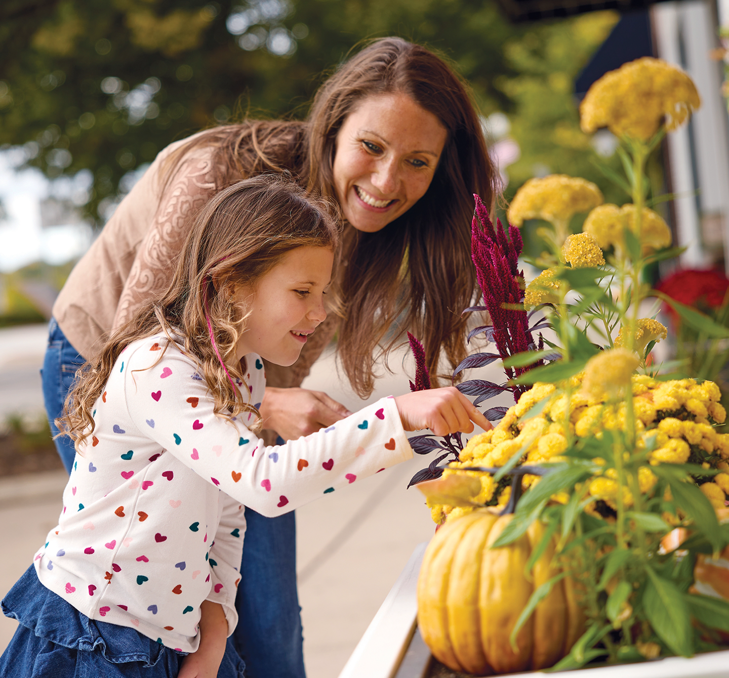 A woman and a child looking at an autumn flower arrangement.