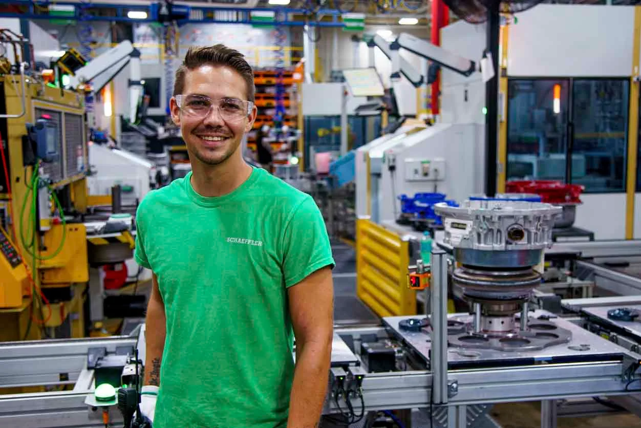 Meet Our Team - a man smiling in a factory wearing goggles