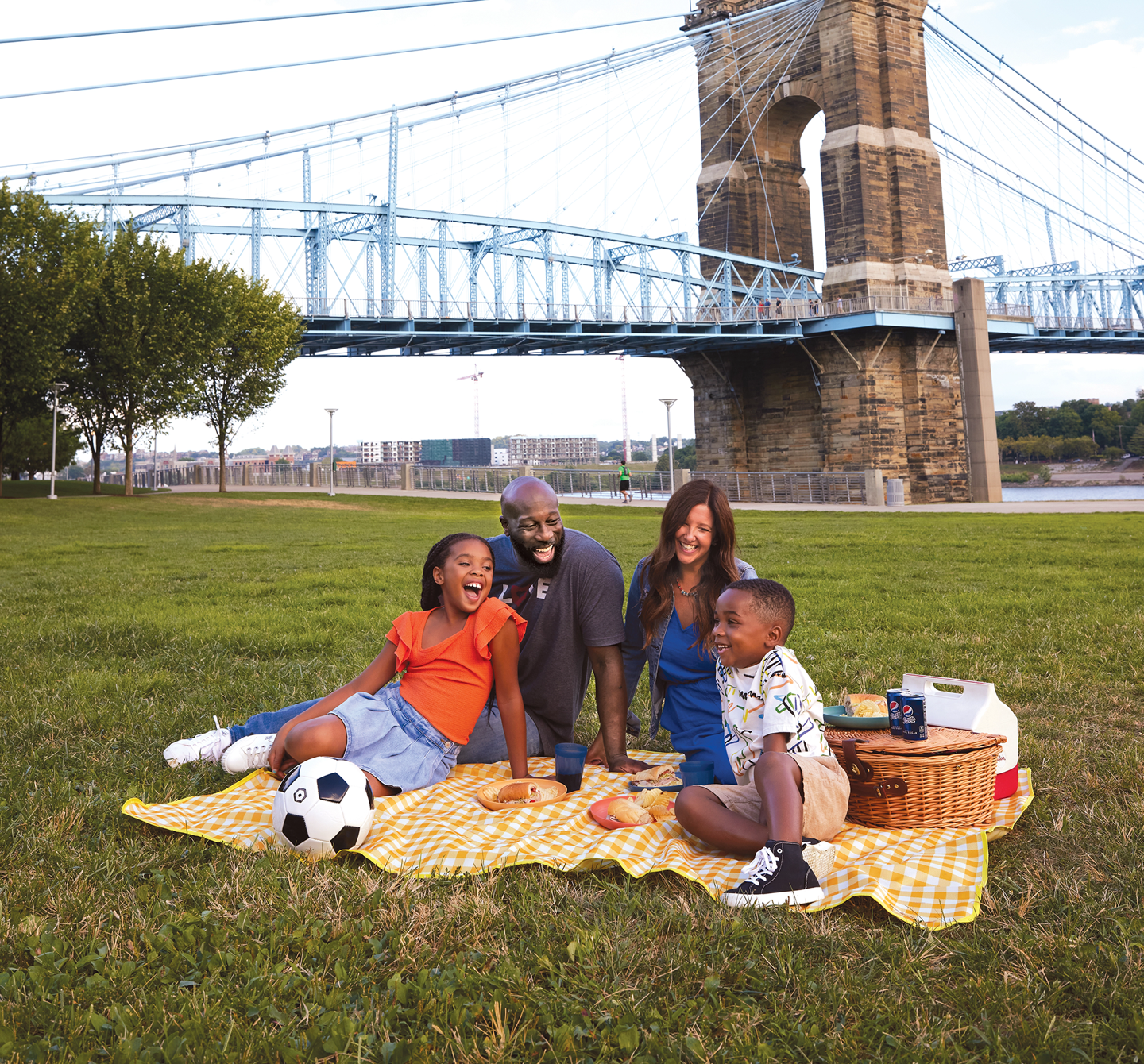 A family of four having a picnic by a bridge on the river