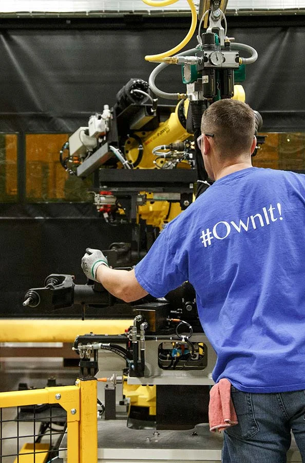 A man working on equipment with #OwnIt! on his shirt