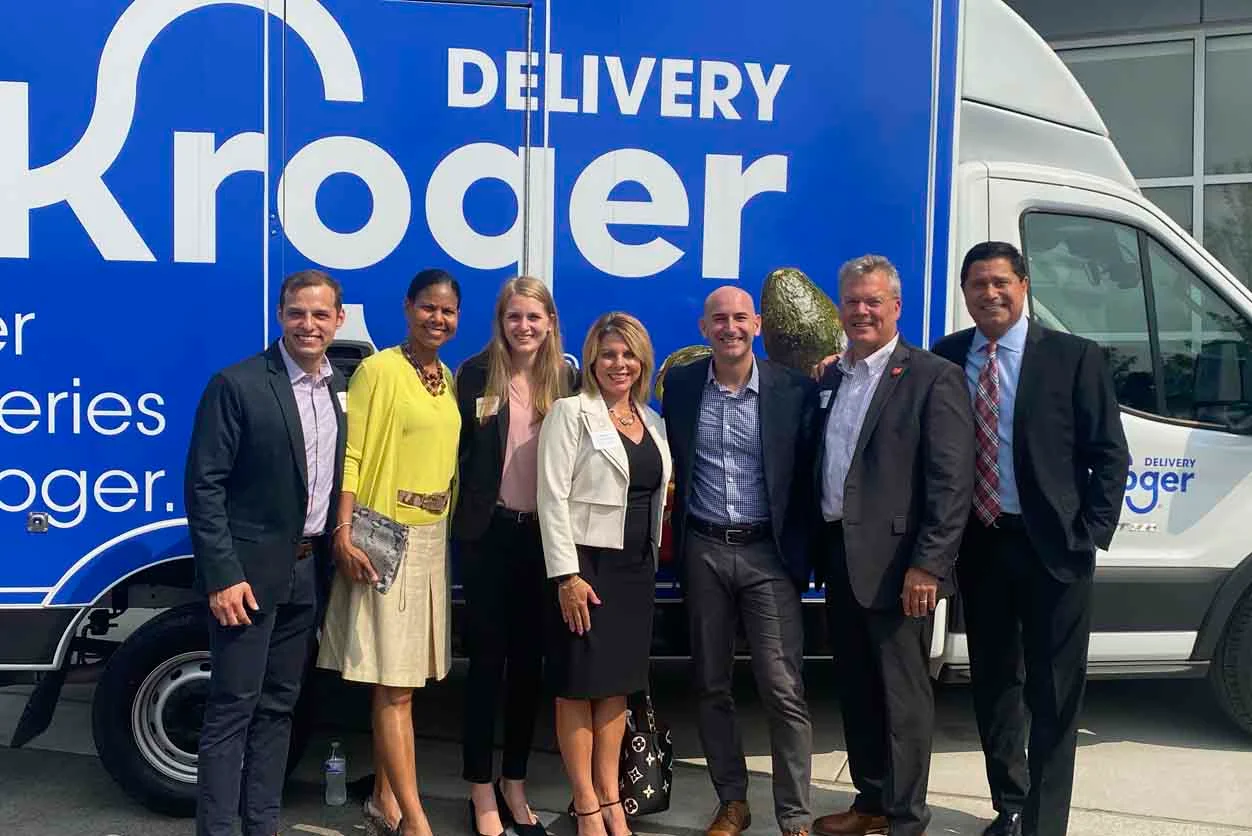 A group of people standing in front of a Kroger delivery truck