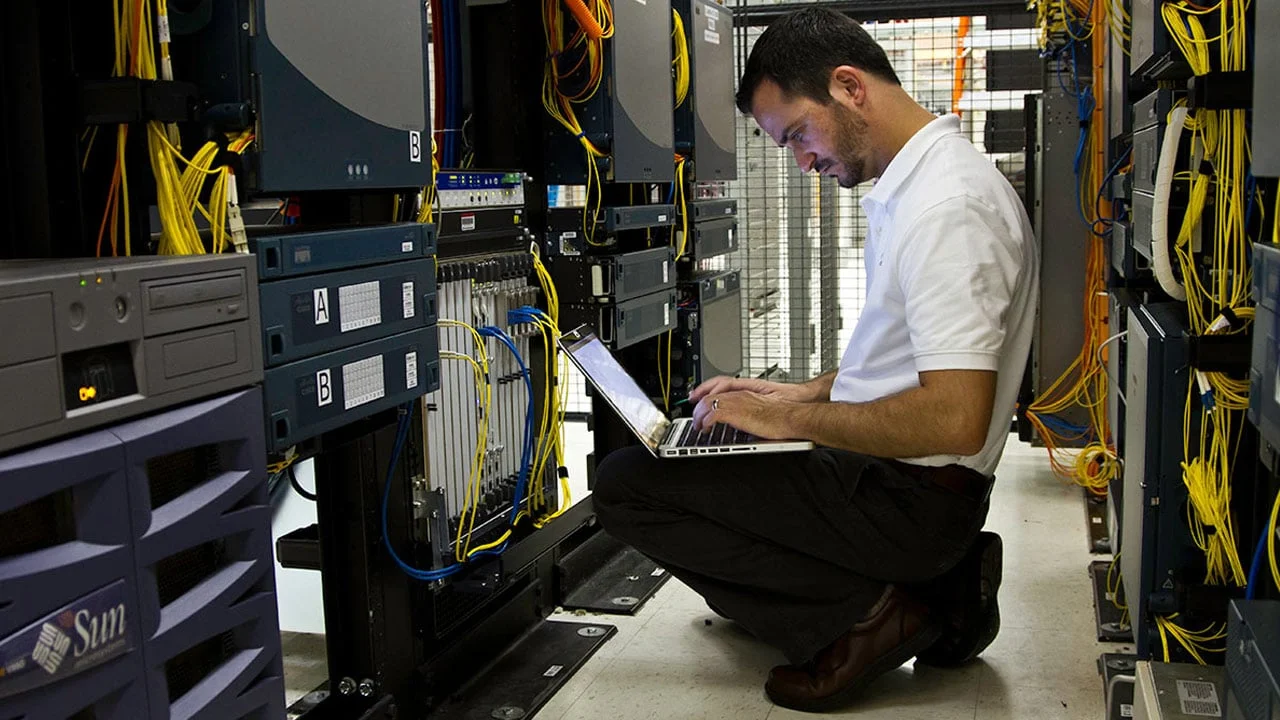Man working on laptop in server room