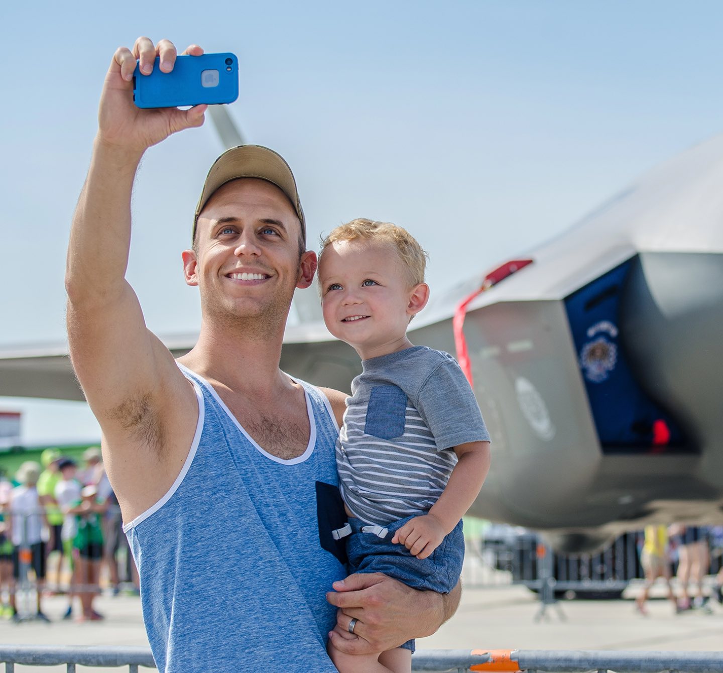 A man holding a child and taking a selfie at the Dayton Air Show