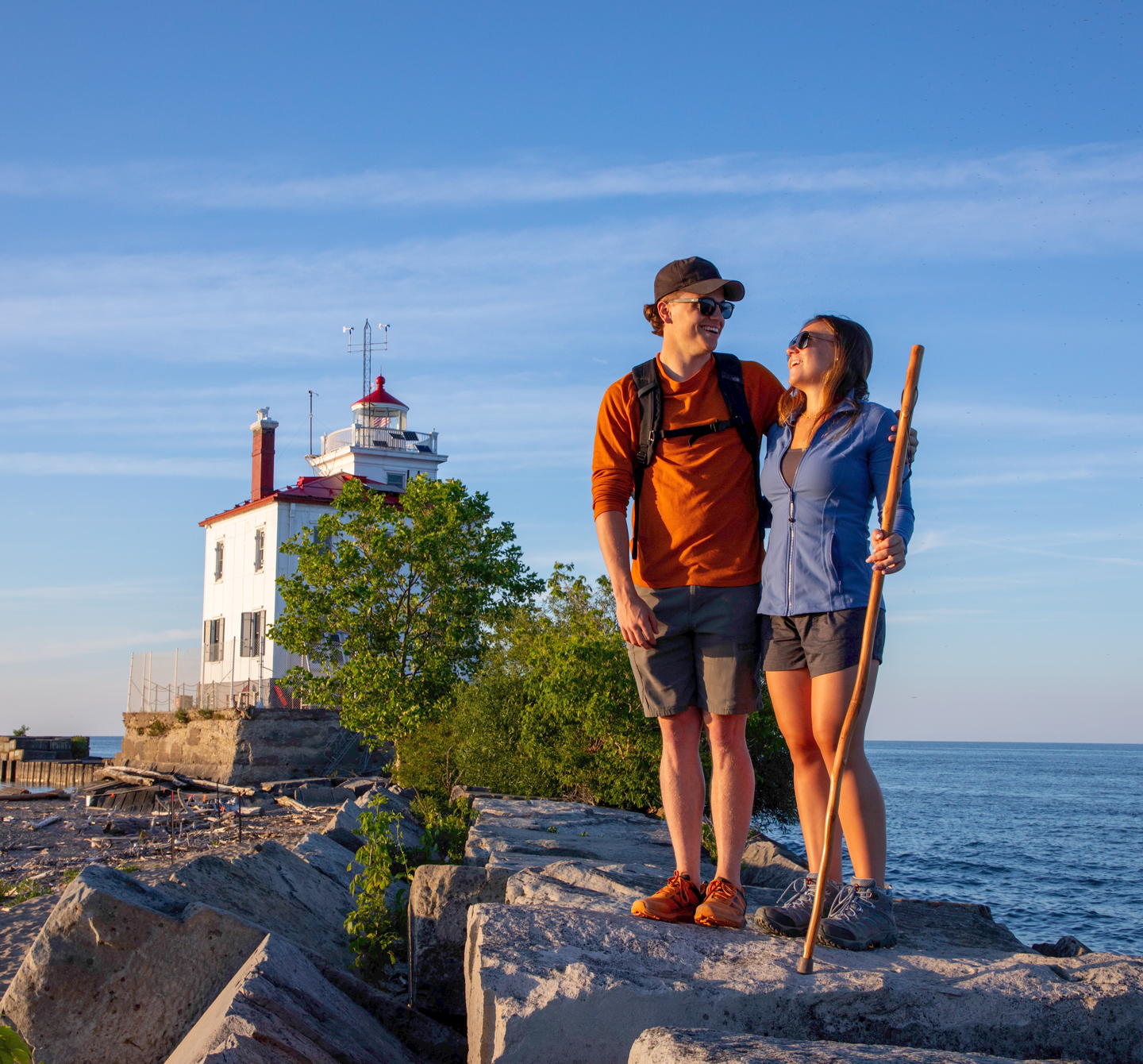 A couple standing on a rock together by a lighthouse at the lake